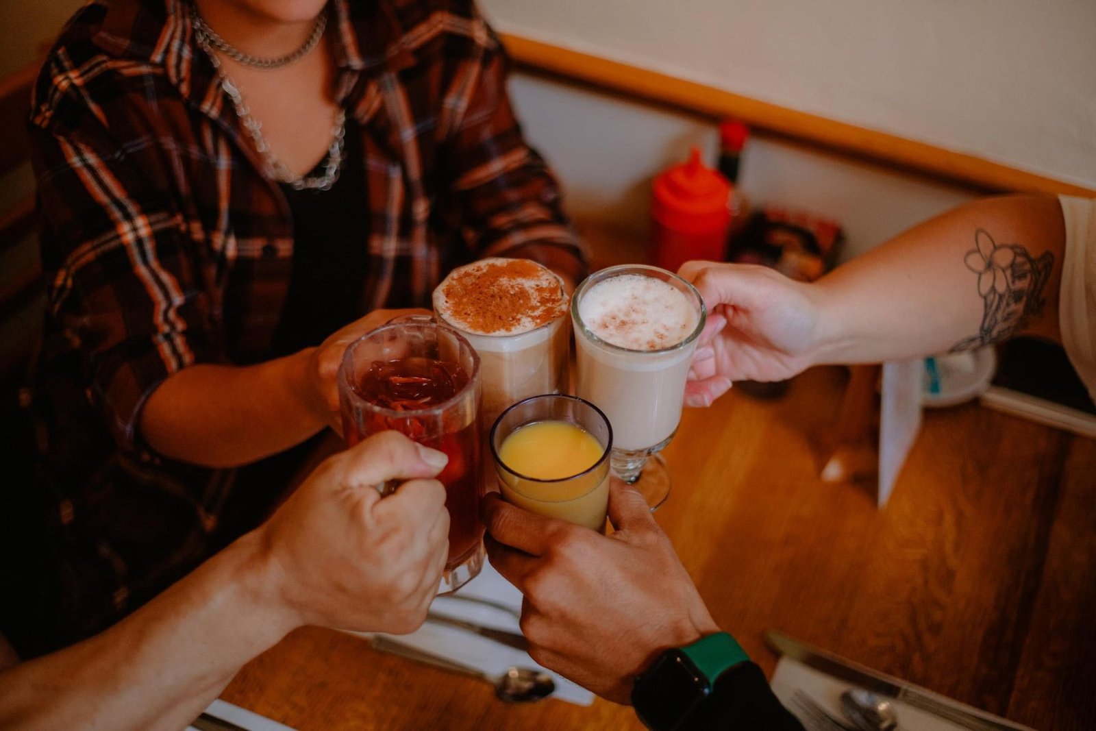 Friends toasting mimosas and lattes in a cozy booth