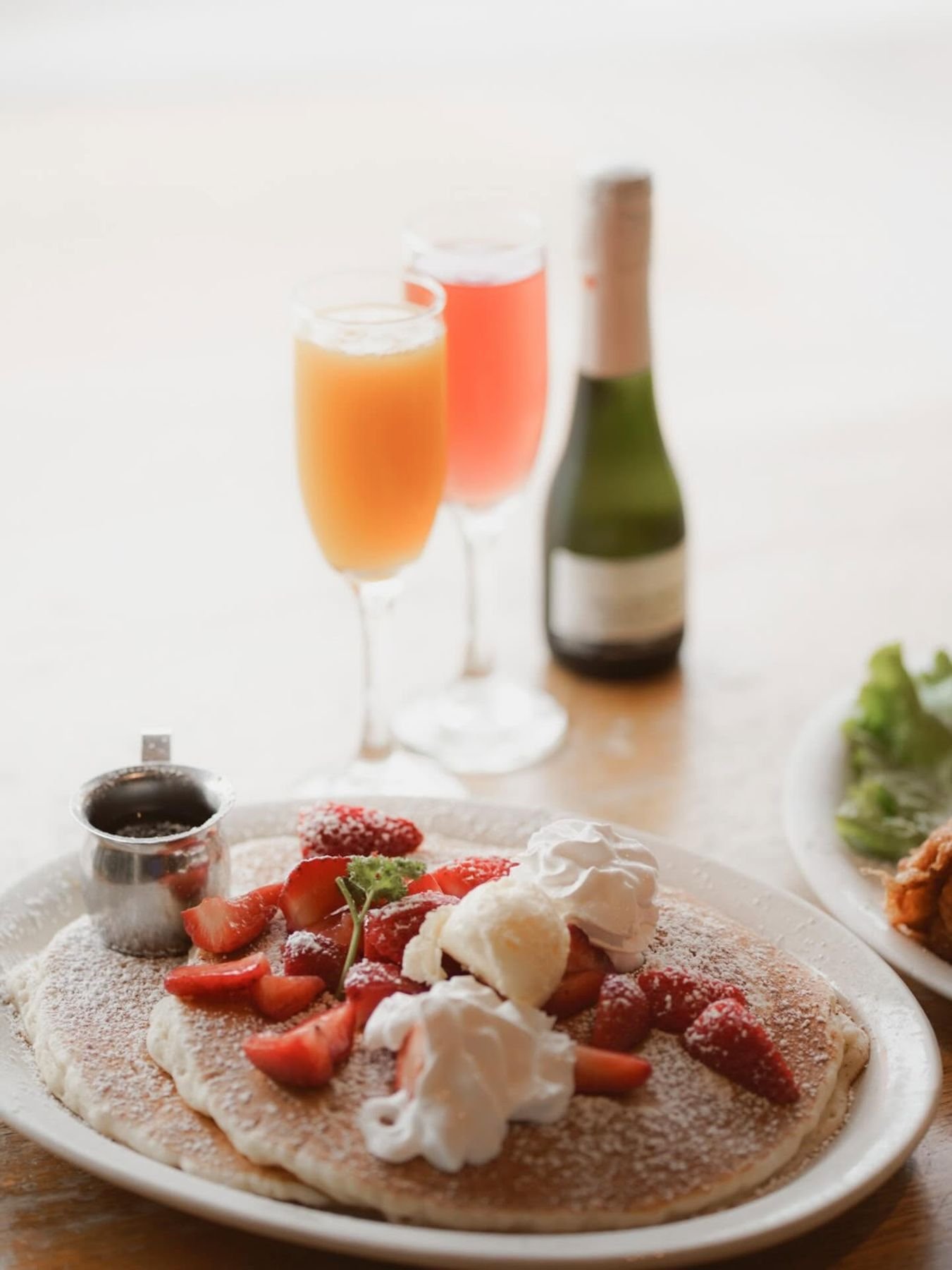 Stack of pancakes with fresh strawberries and mimosas